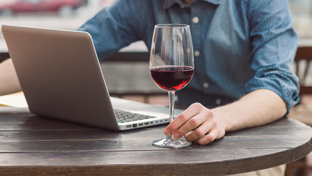 Red wine glass with laptop sat at table