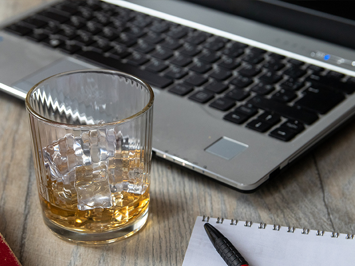 Laptop on design with whiskey in glass