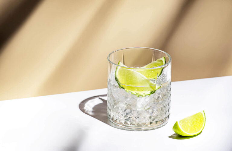 Gin in glass with ice and lime on table