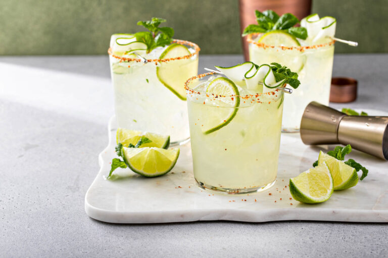 Tequila margarita cocktails with salt, lime and mint on table