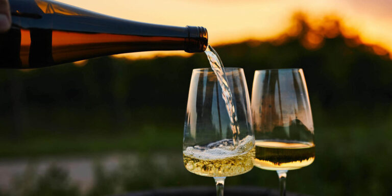 Two glasses of white wine being poured