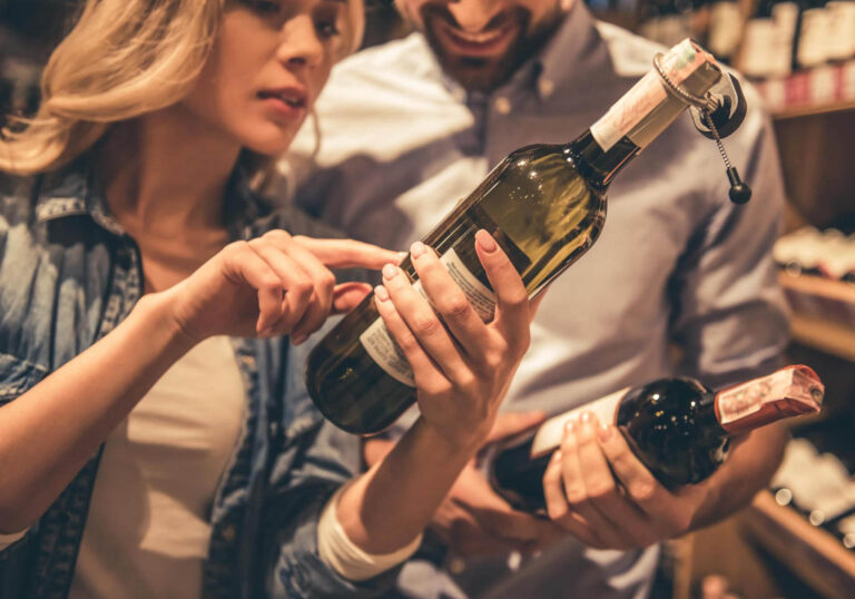 Woman and man looking at wine label in shop