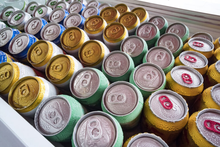 Beer cans Fresh from the fridge. Lots of aluminium cans in the ice in the open fridge. Drops of water on a cold can of drink